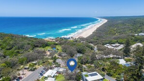 Vista aérea de una zona costera con playa, vegetación densa y una ubicación señalada.