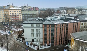 A multi-story building with a mix of brick and white facades, featuring a central courtyard with a small pool and a flagpole. - Wawel Kossak Residence Loft Studio (Kraków)