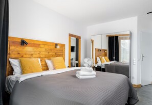 A hotel room with a large bed, wooden headboard, and a mirror. - Wawel Kossak Residence Loft Studio (Kraków)