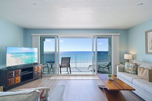 The coastal-inspired living space features comfortable seating, flat-screen TV, and floor-to-ceiling sliding doors to the beach balcony.