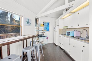 A modern kitchen with white cabinets, a wooden table, and bar stools.