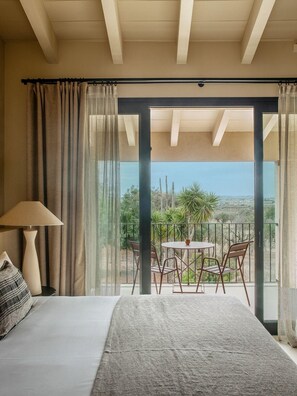 A bedroom with a bed, a lamp, and a view of a balcony with chairs and a table. - The Lodge Mallorca (Sa Pobla)