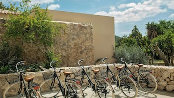 Una hilera de bicicletas estacionadas frente a un muro de piedra, con un cielo despejado al fondo.