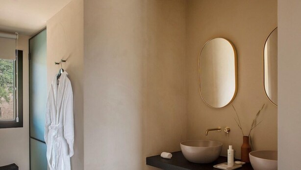 A modern bathroom with a large mirror, two sinks, and a robe hanging on the wall. - The Lodge Mallorca (Sa Pobla)