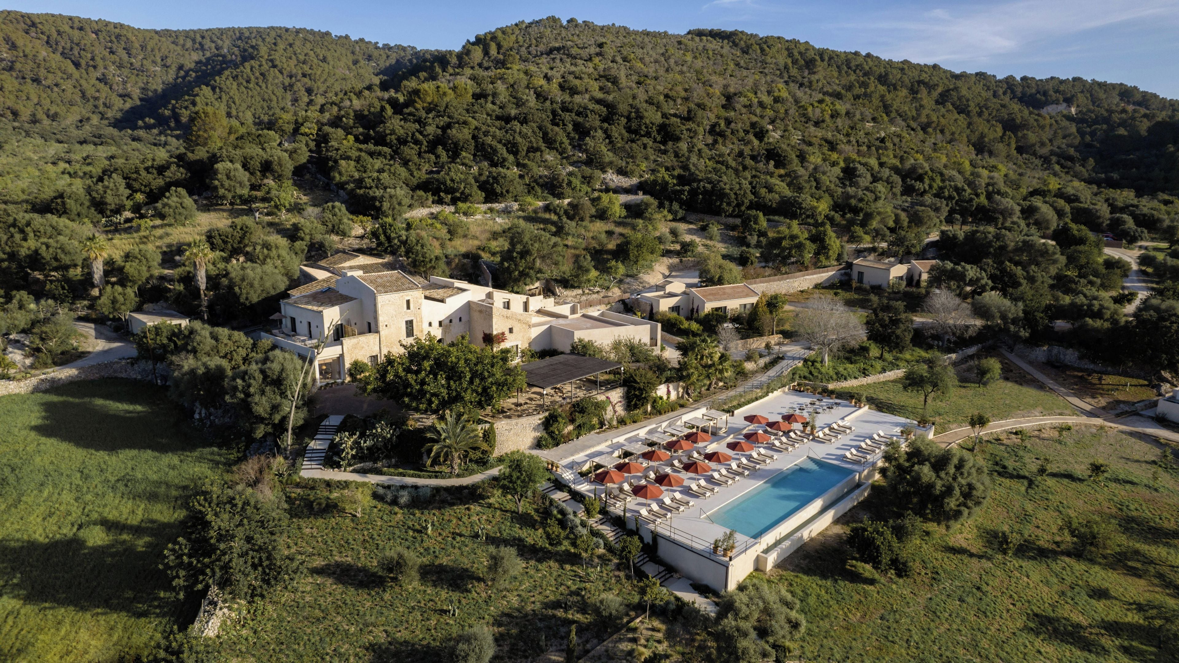 Un resort con varias edificaciones, piscina y montañas al fondo.