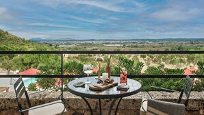 A balcony with a table set for two, overlooking a scenic landscape with hills and a distant town. - The Lodge Mallorca (Sa Pobla)