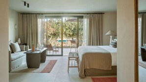 A hotel room with a bed, a sofa, a small table, and a chair. There is a view of the outdoors through a glass door. - The Lodge Mallorca (Sa Pobla)