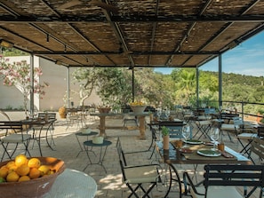 An outdoor patio area with tables and chairs, a bowl of oranges, and a view of the surrounding landscape. - The Lodge Mallorca (Sa Pobla)
