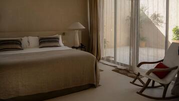 Una habitación de hotel con una cama, una silla, una lámpara y vistas al exterior.