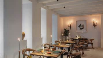 Comedor con varias mesas dispuestas para una comida, con velas, copas de vino y platos.