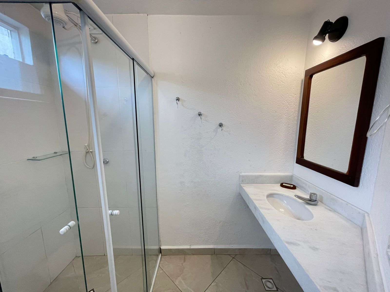 A modern bathroom with a glass shower enclosure, a white vanity with a sink, and a large mirror.
