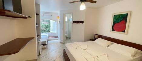 A hotel room with a bed, a ceiling fan, a bathroom, and a view of the outdoors.