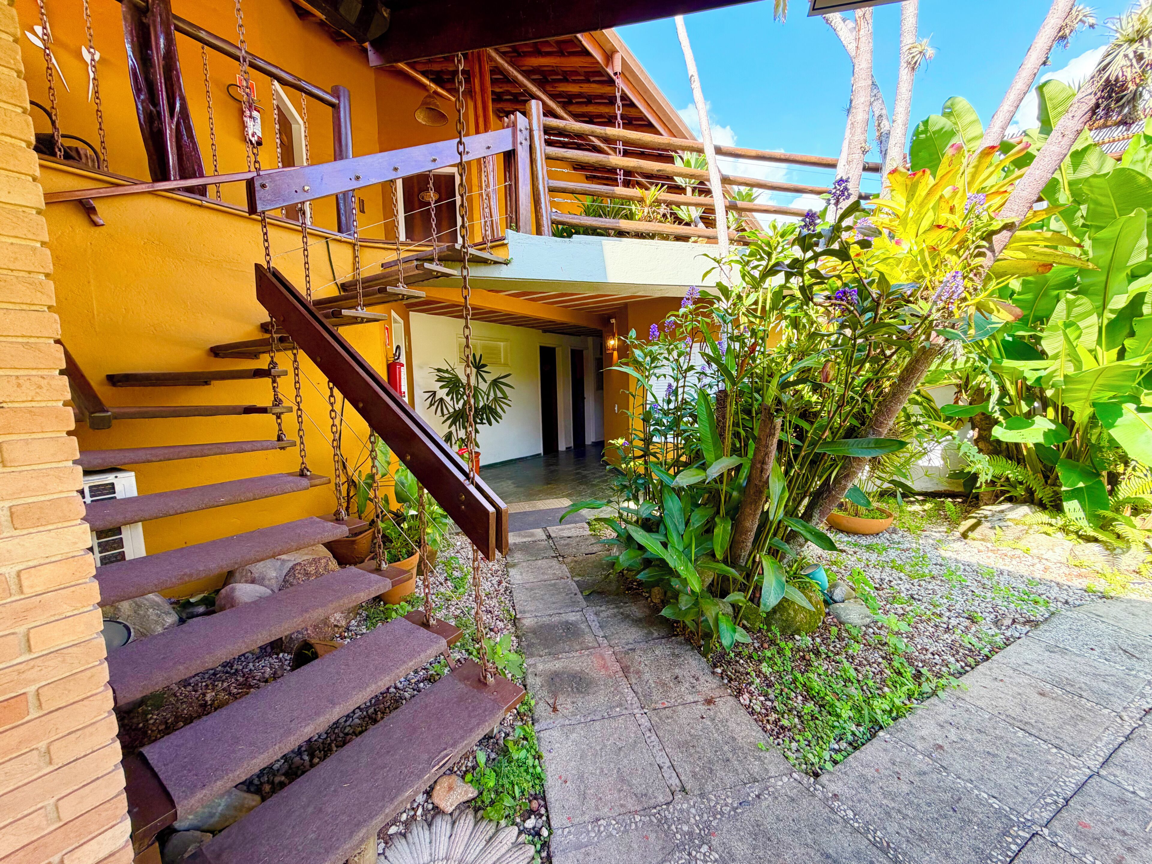 Escada que leva a um deck de madeira com vista para um jardim.