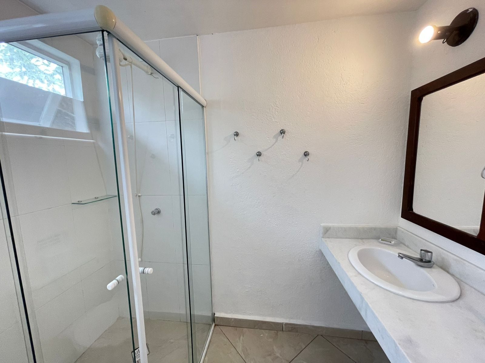 Un baño moderno con cabina de ducha de vidrio, lavamanos blanco y un espejo grande.