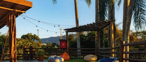 An outdoor seating area with wooden pergolas, string lights, and large bean bags.