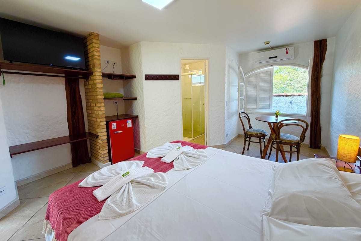 Une chambre d’hôtel équipée d’un lit, d’un bureau, d’une chaise, d’une télévision, d’une armoire et d’une fenêtre.