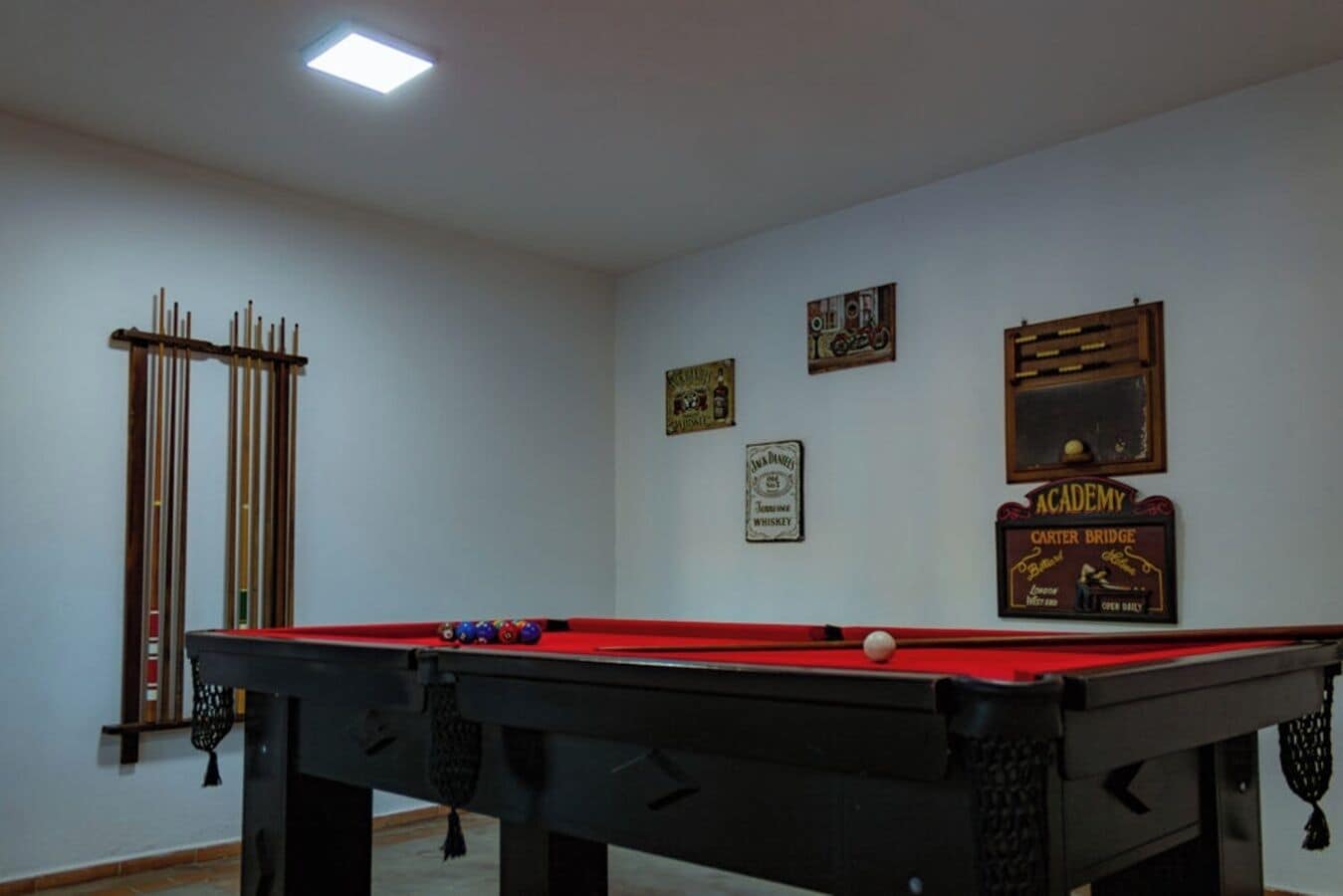 A pool table with balls, a billiard rack, and wall decorations including signs.