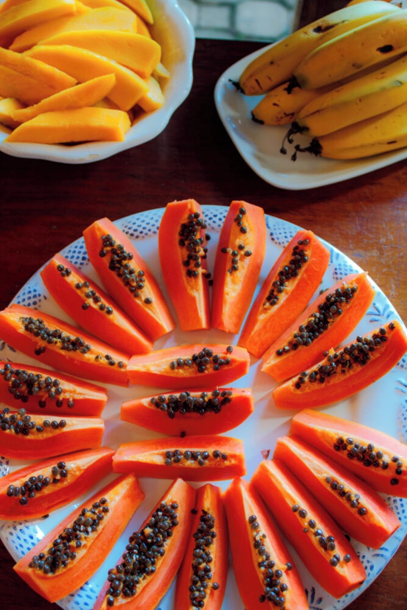 A plate of sliced papaya with black seeds on a decorative plate.