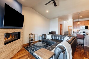 A modern living room with a fireplace, leather sofa, and a flat-screen TV. - Min to Ski & Lake, 3BR Sleeps 9 + Hot Tub in Black Rock Ridge. (Kamas)