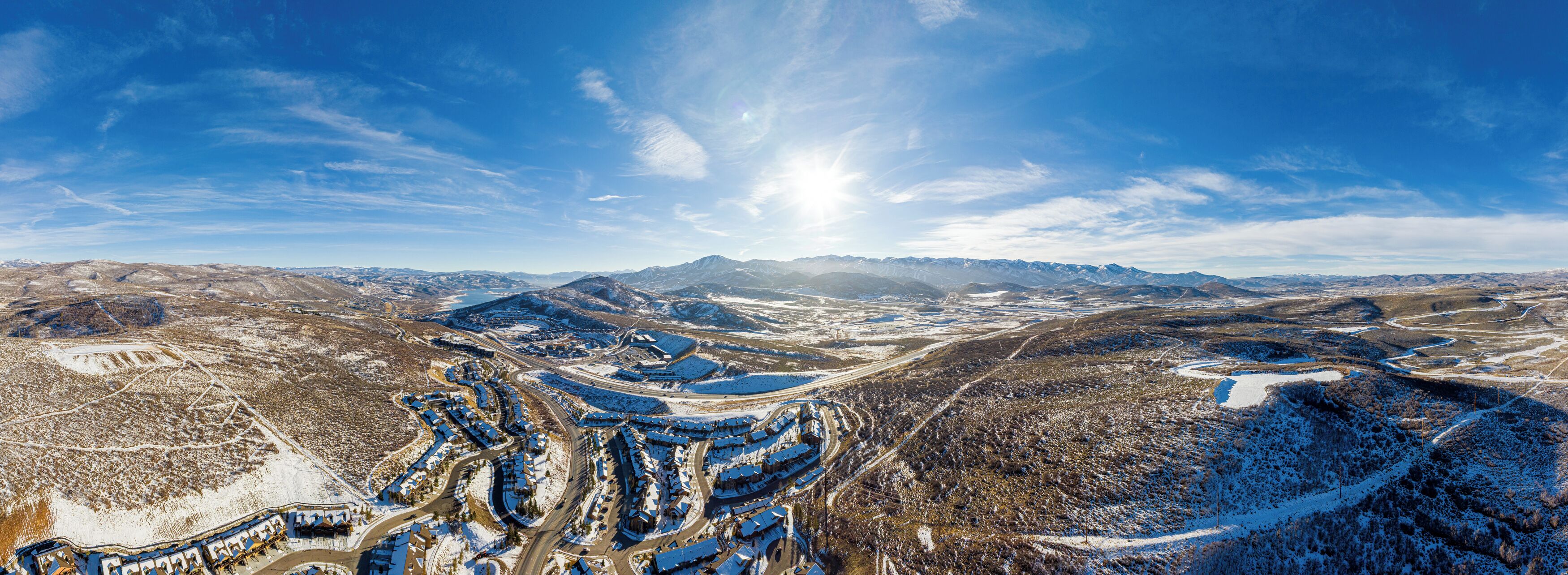 A panoramic view of a mountainous area with a snow-covered landscape and a series of buildings with blue roofs.