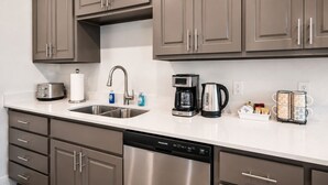 A modern kitchen with stainless steel appliances, a double sink, and a coffee maker. - Luxury New-Build Suite • Downtown • Convention (Hot Springs)