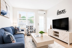A modern living room with a sofa, armchair, coffee table, TV, and decorative wall art. - Stylish New-Build Suite • Downtown Hot Springs (Hot Springs)