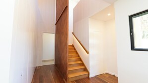Ein modernes Interieur mit einer Holztreppe, weißen Wänden und einem Fenster.