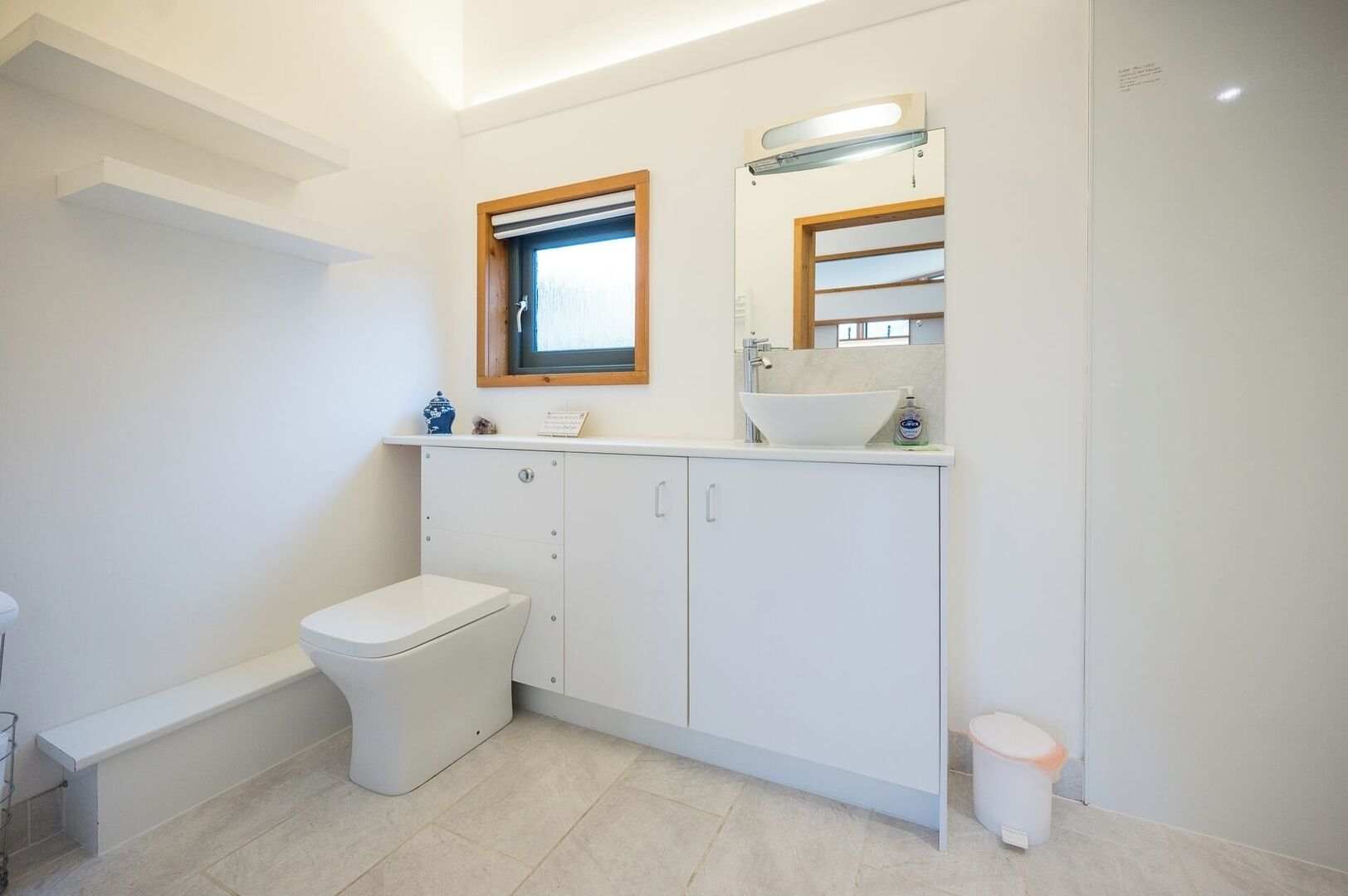 A modern bathroom with a toilet, a sink, and a mirror.