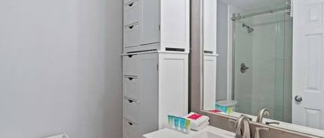 A modern bathroom with a white sink, mirror, and storage cabinets.