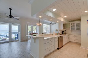 A spacious kitchen with a large island, white cabinetry, and a view to the outside. - Sunset Overlook - Waterfront Condo at Harbour Place with Sunset View (Key West)
