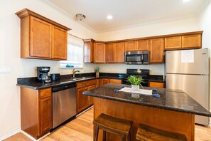 A modern kitchen with wooden cabinets, stainless steel appliances, and a granite countertop. - Ocean View l Pet Friendly (Gilchrist)