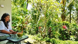 A person sitting at a table with a green glass, a mobile phone, and a coconut. - Jepun Sesandan Yoga & Retreat (Selemadeg)