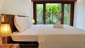 A neatly made bed with white linens, a wooden headboard, and a bedside lamp. - Jepun Sesandan Yoga & Retreat (Selemadeg)