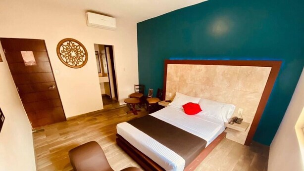 A bedroom with a bed, two chairs, a wooden door, and a wall decoration. - Motel Passion (Córdoba)