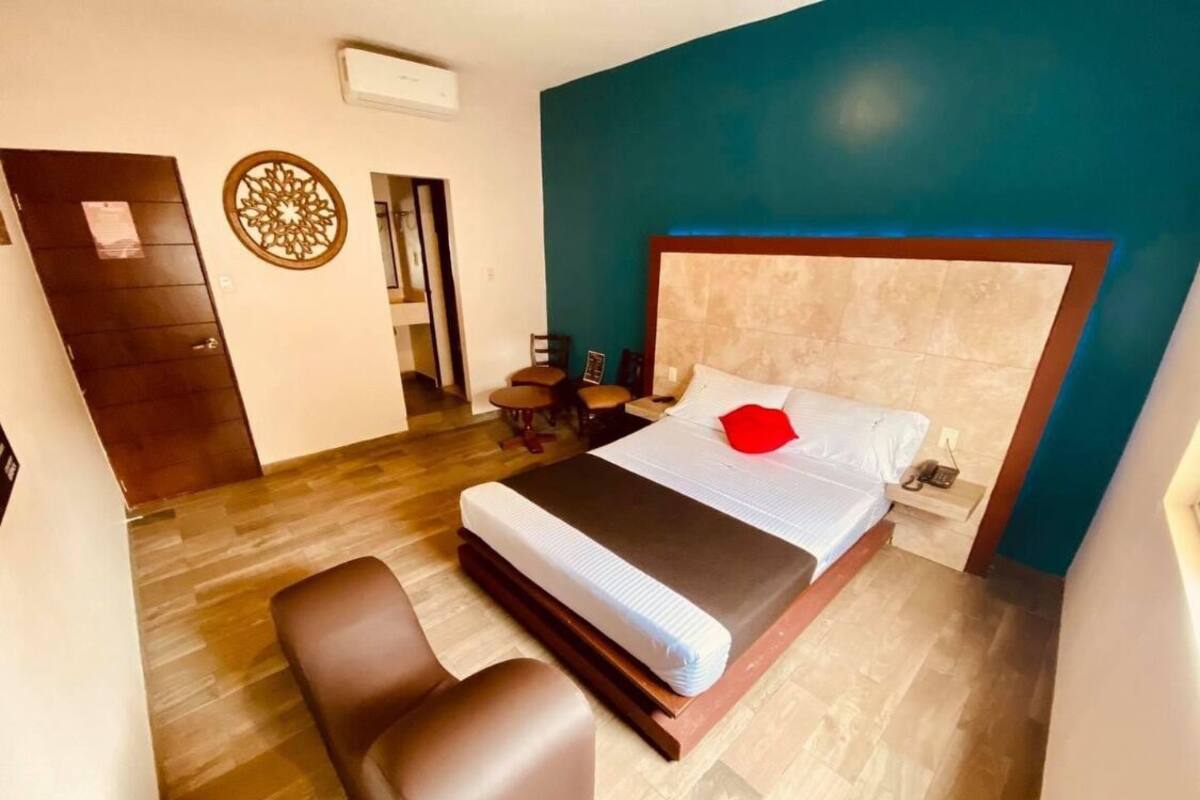 Un dormitorio con cama, dos sillas, una puerta de madera y un adorno en la pared.