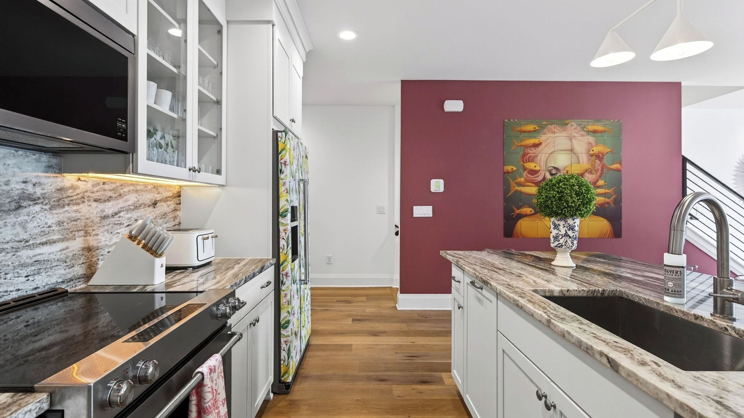 A modern kitchen with a marble countertop, stainless steel appliances, and a wooden floor.