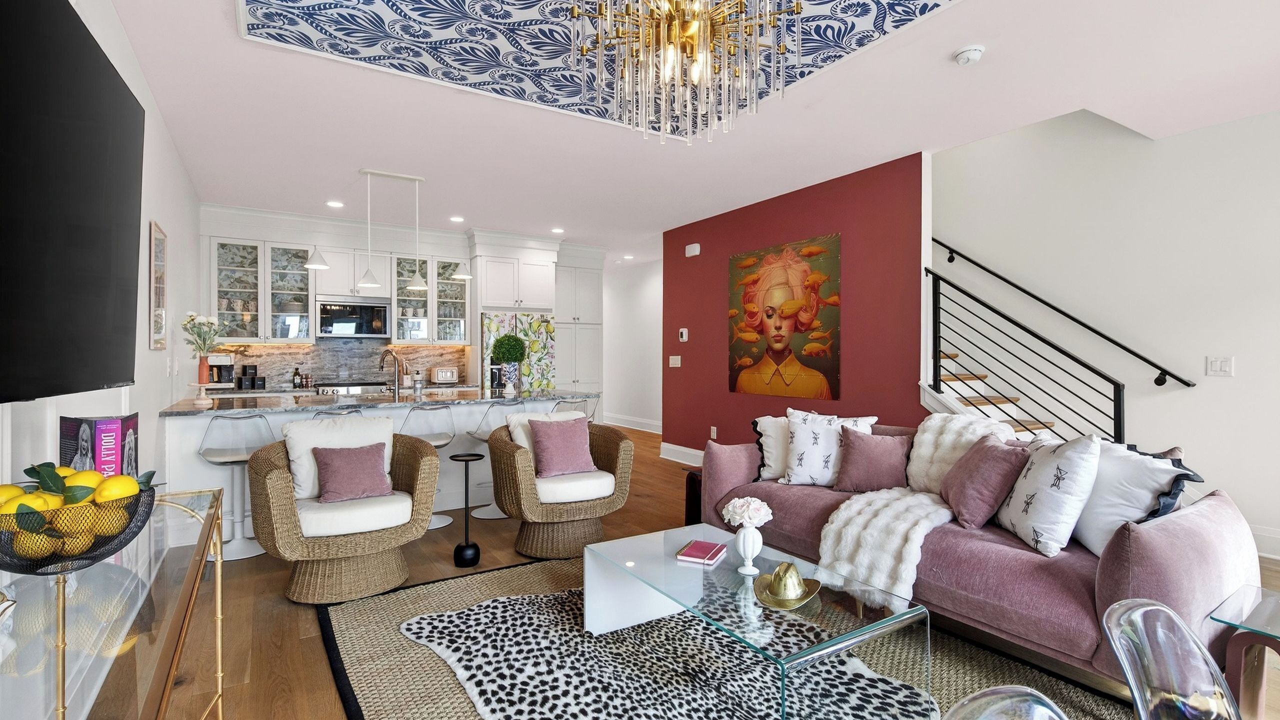 Un salon moderne avec un canapé, deux fauteuils, une table basse et une cuisine en arrière-plan.