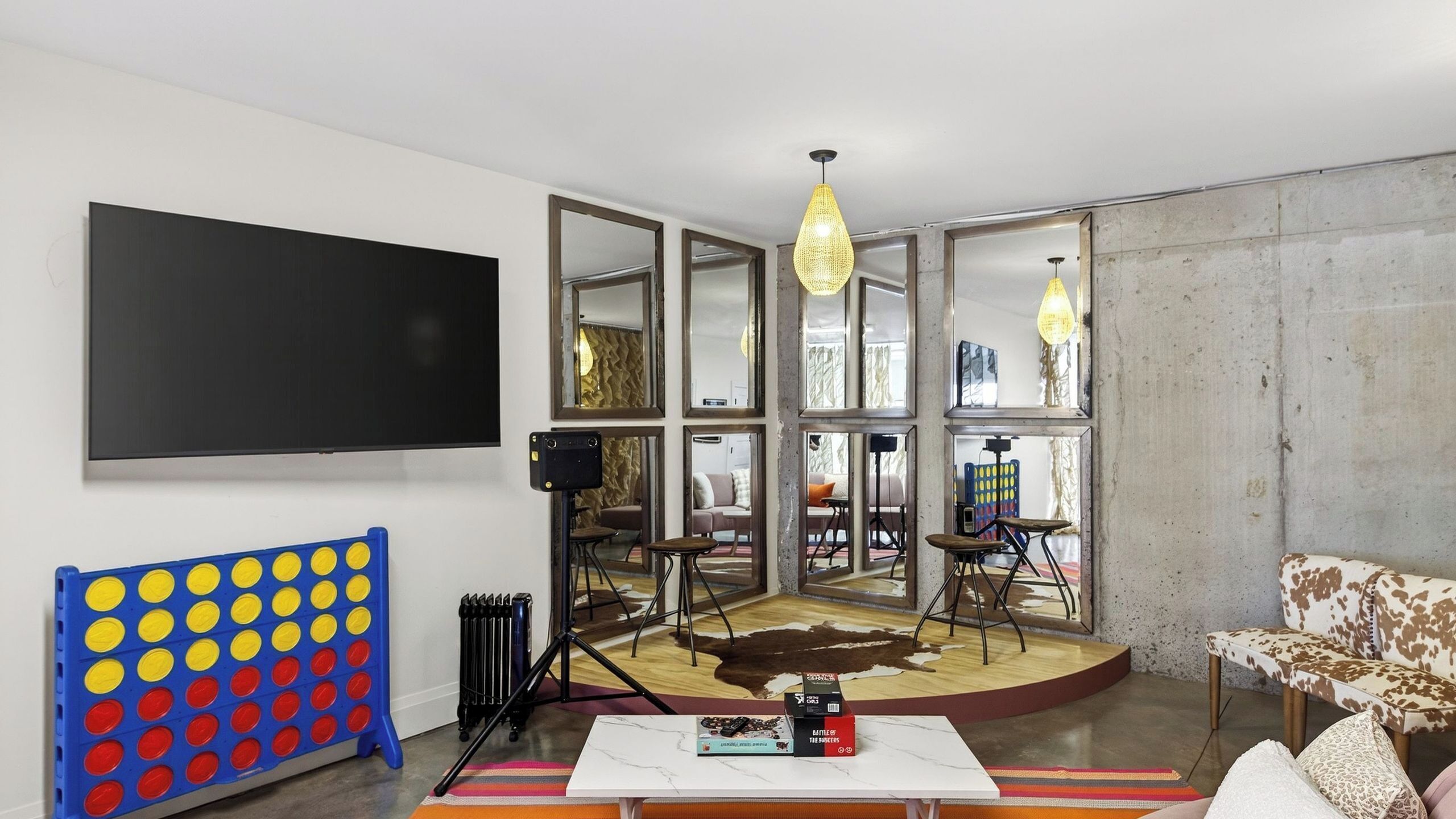 A modern living room with a large TV, a coffee table, a sofa, and a unique seating area with a cowhide rug.