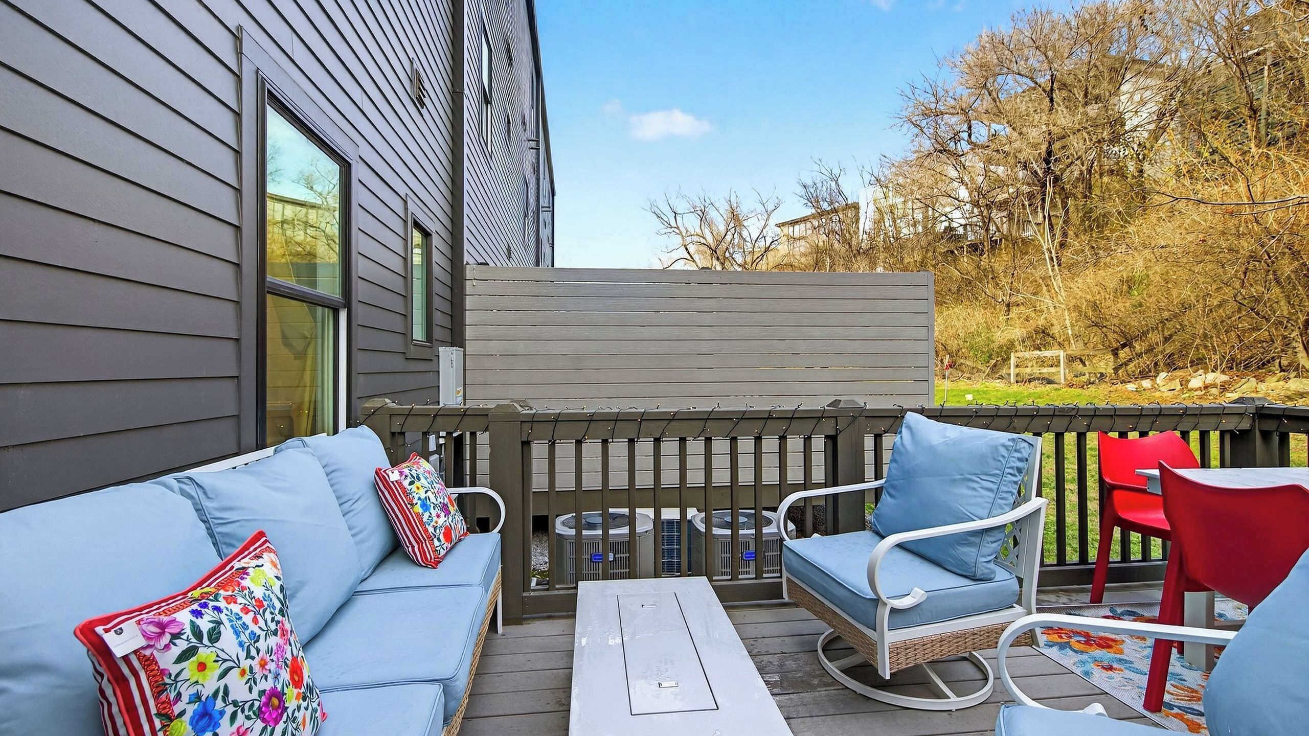 Eine Terrasse im Freien mit einem blauen Sofa, einem Korbstuhl und einem roten Stuhl.