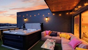 A rooftop terrace with a hot tub, a cushioned seating area, and string lights. - Girls Night Out by Avantstay Private Karaoke Lounge + Hot Tub + Rooftop + Downtown Views (Nashville)