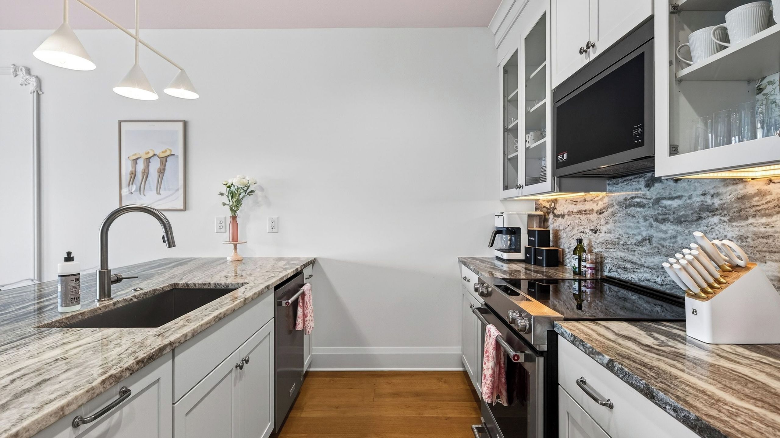 A modern kitchen with a marble countertop, stainless steel appliances, and a built-in oven.
