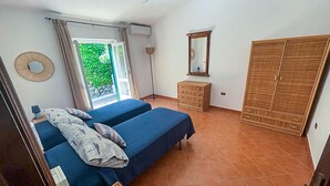 Een slaapkamer met twee bedden, een kledingkast, een spiegel en een raam met gordijnen.