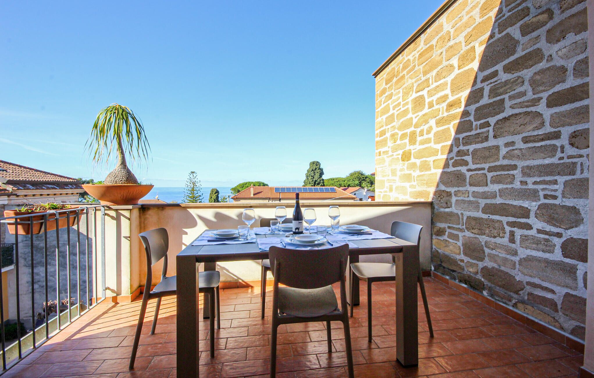 An outdoor dining area with a table set for two, overlooking a scenic view of the sea.