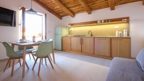 A compact kitchen with wooden cabinets, a built-in oven, and a sink. There is a dining area with a table and chairs, and a sofa in the living area. - Gorgeous apartment in San Marco di Castellab (San Marco di Castellab)