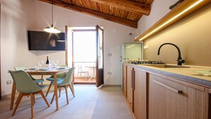 A modern kitchen with wooden cabinets, a built-in stove, and a large sink. There is a dining area with a table and chairs, and a television mounted on the wall. - Gorgeous apartment in San Marco di Castellab (San Marco di Castellab)