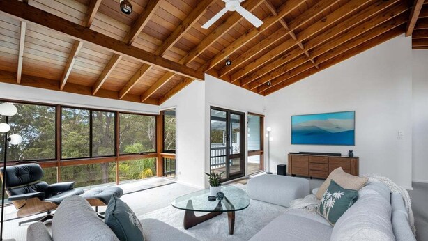 A modern living room with a high ceiling, large windows, and a cozy seating area.