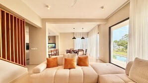 Ein modernes Wohnzimmer mit Ecksofa, Essbereich und Blick auf einen Swimmingpool.