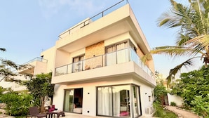Ein modernes, zweistöckiges Haus mit Schwimmbad, Außenbereich und üppiger Bepflanzung.
