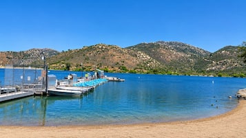 A marina with boats docked, a sandy beach, and a mountainous backdrop.