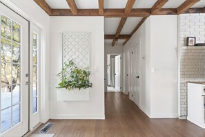 Un couloir avec des poutres en bois, des murs blancs et une porte blanche.